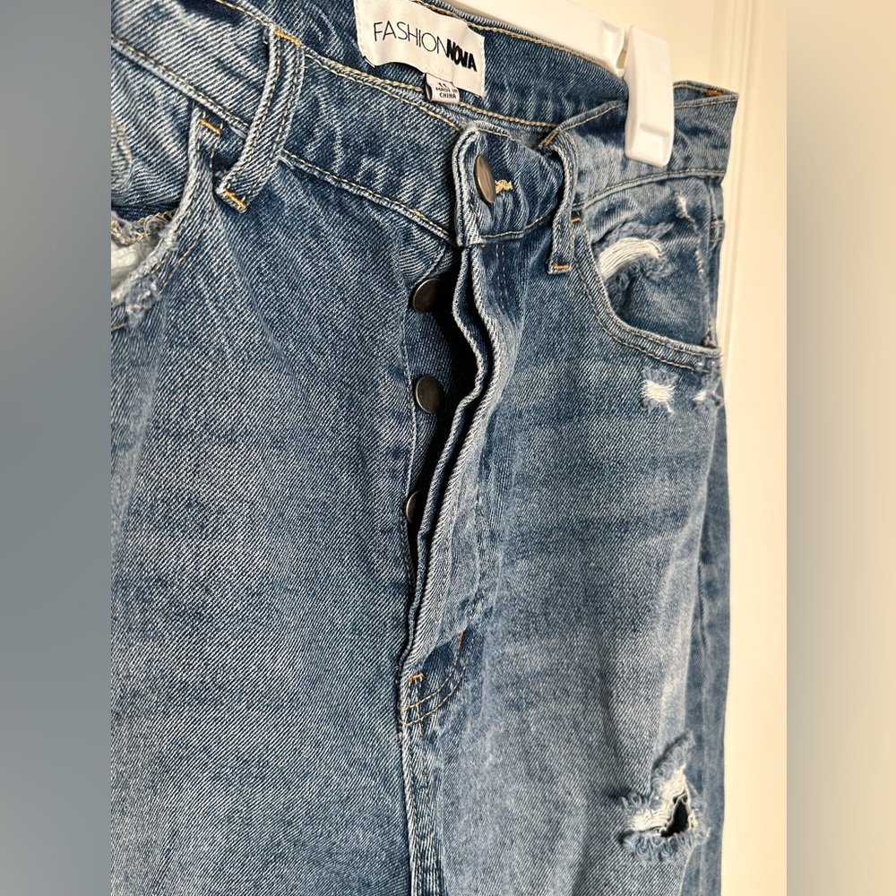 Wide leg, high waist denim jeans with holes and rips. Buttons instead of zipper